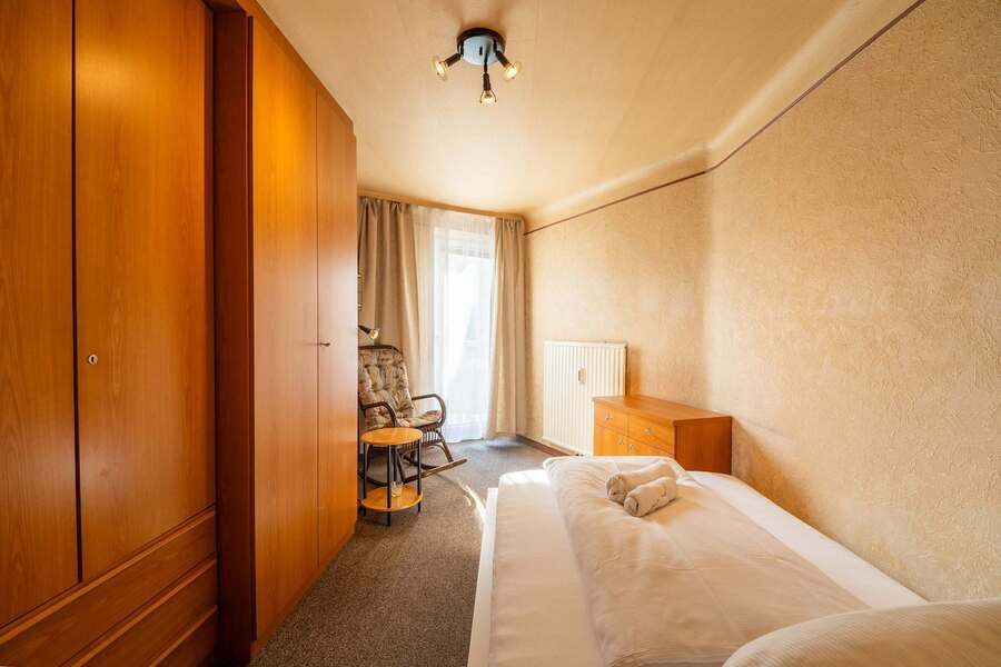 Second Bedroom in Natural Light - Spacious, Carpeted, with a Rocking Chair for Reading or Reflection