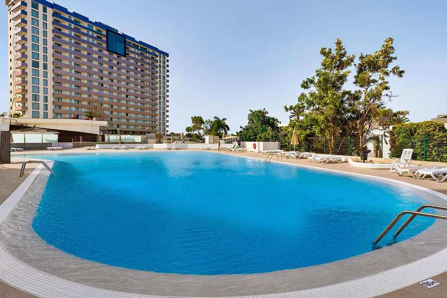 Resort-Style Pool Area with Sun Loungers and Open-Air Relaxation Space