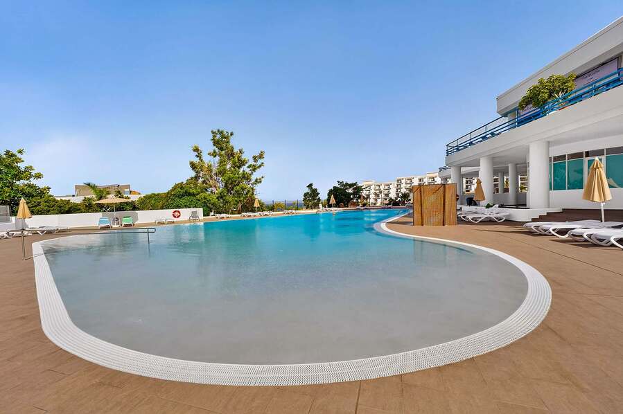 Resort-Style Pool Area with Sun Loungers and Open-Air Relaxation Space