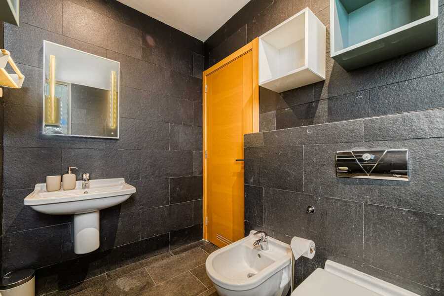 Stylish Black-Tiled Bathroom with Bathtub – Sleek Design and Natural Light